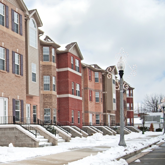A row of modern, multi-story brick and siding townhouses during the winter